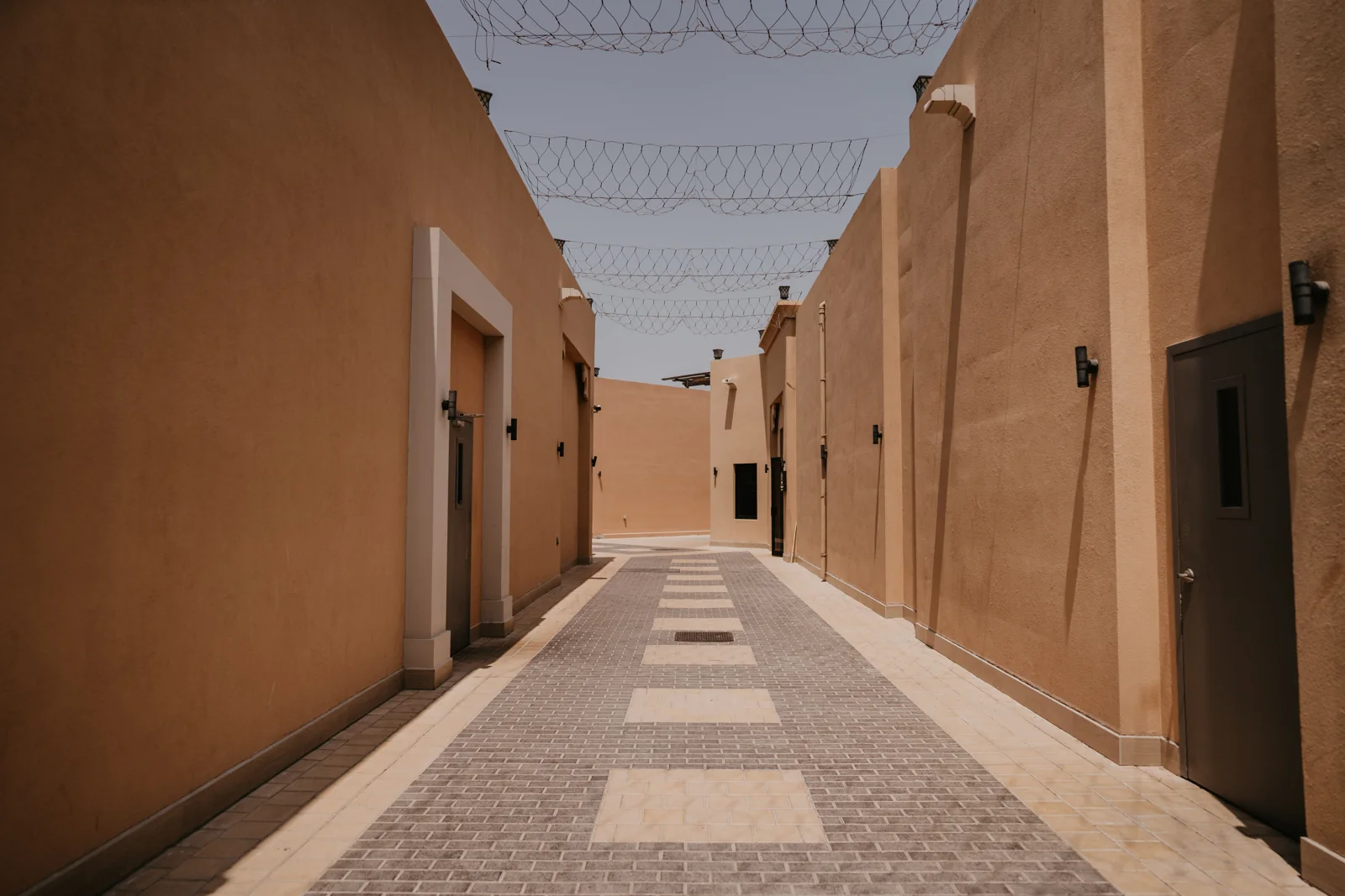 Sunlit walkway between sand-coloured buildings